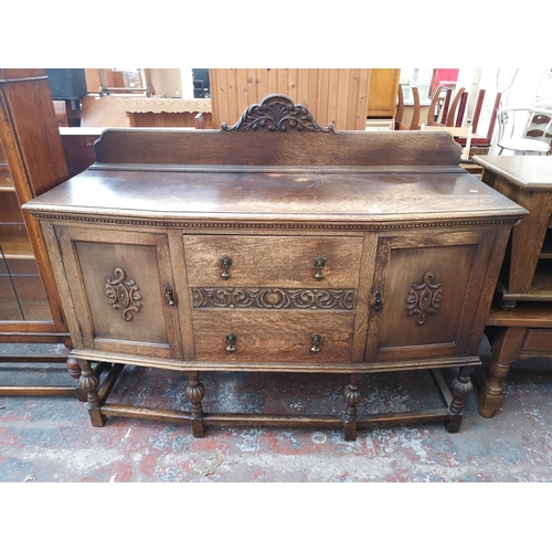 1053 - An early 20th century carved oak sideboard with two central drawers, two outer cupboard doors and ba... 