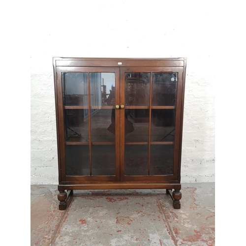 1017 - An oak two door glazed bookcase with baluster supports and three internal shelves - approx. 105cm hi... 