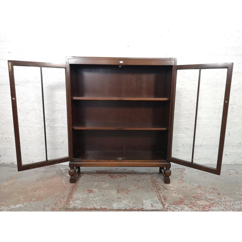 1017 - An oak two door glazed bookcase with baluster supports and three internal shelves - approx. 105cm hi... 