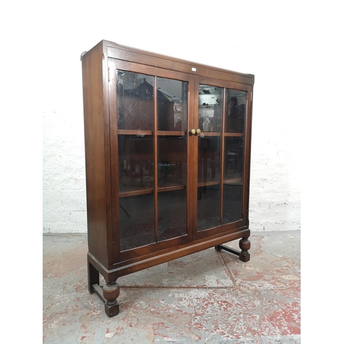 1017 - An oak two door glazed bookcase with baluster supports and three internal shelves - approx. 105cm hi... 