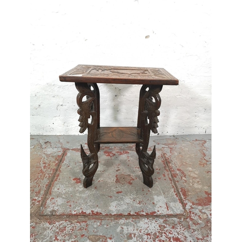 1038 - An Indian heavily carved teak two tier side table - approx. 64cm high x 51cm wide x 37cm deep