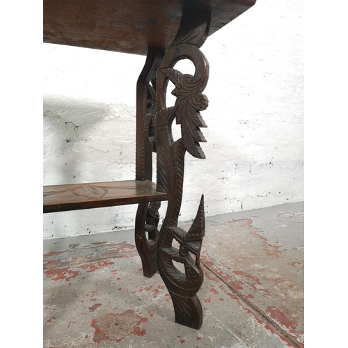 1038 - An Indian heavily carved teak two tier side table - approx. 64cm high x 51cm wide x 37cm deep