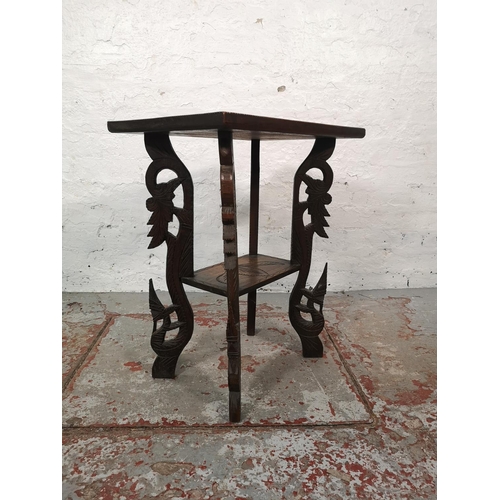 1038 - An Indian heavily carved teak two tier side table - approx. 64cm high x 51cm wide x 37cm deep