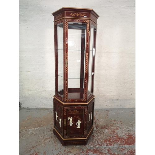 1051 - An Oriental red lacquered hexagonal display cabinet with mother of pearl Geisha girl design and two ... 