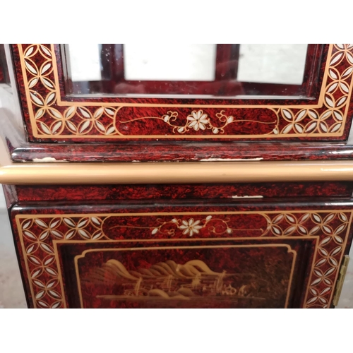 1051 - An Oriental red lacquered hexagonal display cabinet with mother of pearl Geisha girl design and two ... 