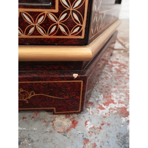 1051 - An Oriental red lacquered hexagonal display cabinet with mother of pearl Geisha girl design and two ... 