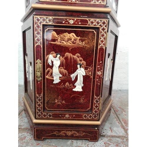 1051 - An Oriental red lacquered hexagonal display cabinet with mother of pearl Geisha girl design and two ... 