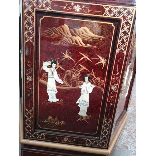 1051 - An Oriental red lacquered hexagonal display cabinet with mother of pearl Geisha girl design and two ... 