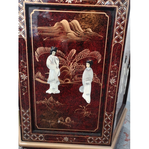 1051 - An Oriental red lacquered hexagonal display cabinet with mother of pearl Geisha girl design and two ... 