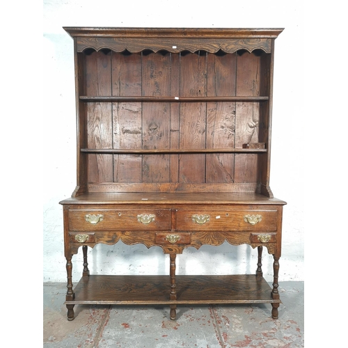 1070 - A George III style oak and elm dresser with upper two tier plate rack, two long drawers and lower sh... 