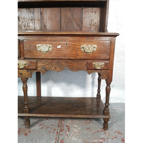 1070 - A George III style oak and elm dresser with upper two tier plate rack, two long drawers and lower sh... 