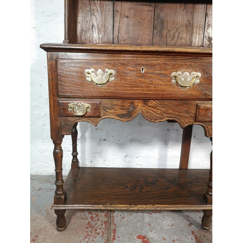 1070 - A George III style oak and elm dresser with upper two tier plate rack, two long drawers and lower sh... 