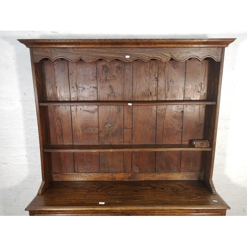 1070 - A George III style oak and elm dresser with upper two tier plate rack, two long drawers and lower sh... 