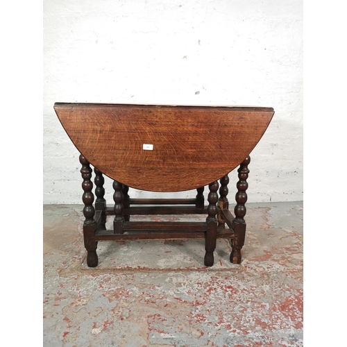 1081 - An 18th century oak drop leaf gate leg oval dining table with barley twist supports - approx. 72cm h... 