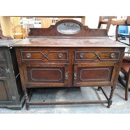 1082 - A 1920s oak mirror back sideboard with two drawers, two cupboard doors, oval bevel edged mirror and ... 