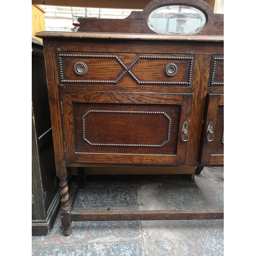 1082 - A 1920s oak mirror back sideboard with two drawers, two cupboard doors, oval bevel edged mirror and ... 