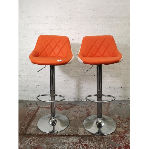 1129 - A pair of modern orange and white leatherette gas lift kitchen bar stools - approx. 104cm high x 46c... 