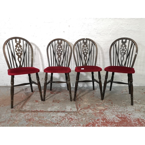 1130 - A set of four oak wheel back dining chairs with red upholstery