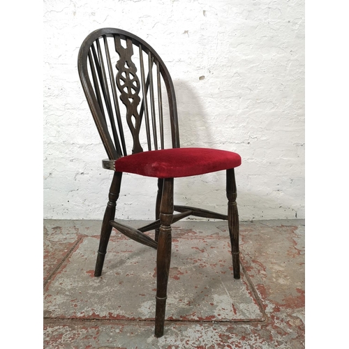 1130 - A set of four oak wheel back dining chairs with red upholstery