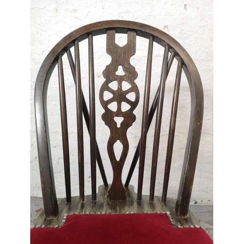 1130 - A set of four oak wheel back dining chairs with red upholstery