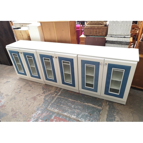 1131 - Three contemporary white painted and blue fabric bedroom display cabinets, each having two glazed do... 