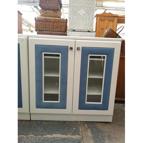 1131 - Three contemporary white painted and blue fabric bedroom display cabinets, each having two glazed do... 