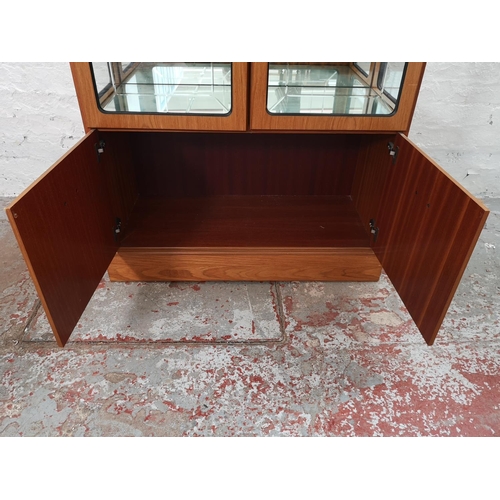 1055B - A late 20th century teak effect display cabinet with two upper bevelled glass doors, two lower cupbo... 