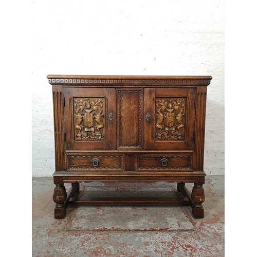 1141B - A 17th century style carved oak side cabinet with two cupboard doors and two lower drawers - approx.... 