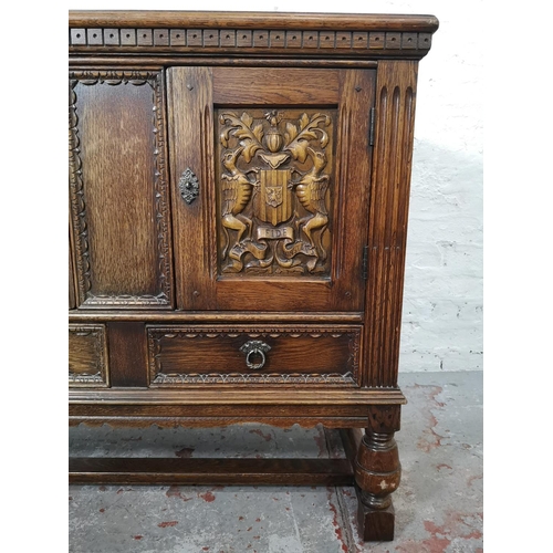 1141B - A 17th century style carved oak side cabinet with two cupboard doors and two lower drawers - approx.... 