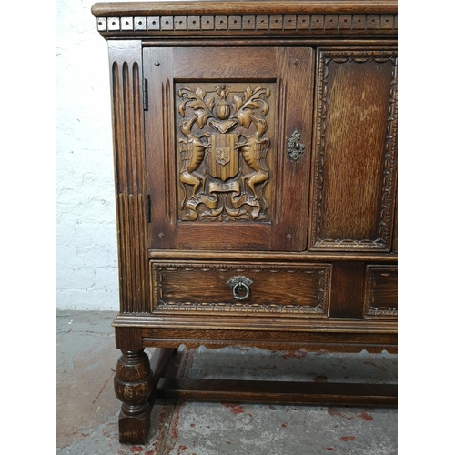 1141B - A 17th century style carved oak side cabinet with two cupboard doors and two lower drawers - approx.... 