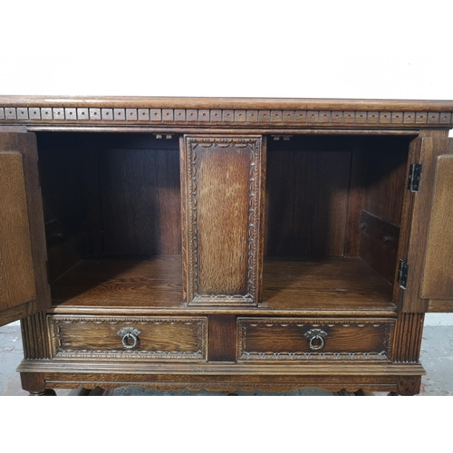 1141B - A 17th century style carved oak side cabinet with two cupboard doors and two lower drawers - approx.... 