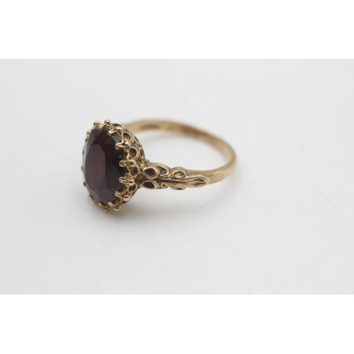 2176 - A 9ct gold oval cut garnet with ornate frame ring, size P - approx. gross weight 4.6 grams