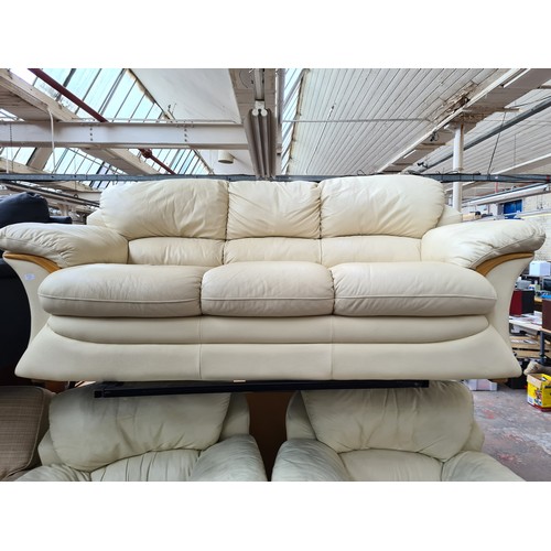 1155B - A modern cream leather and beech three piece lounge suite comprising three seater sofa and two armch... 