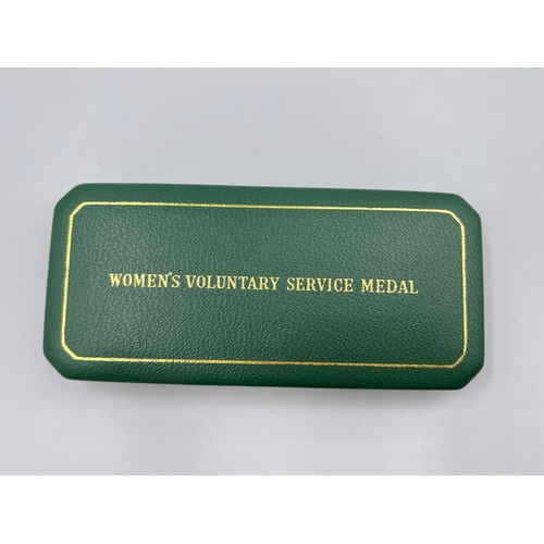 65B - A cased Women's voluntary service medal with certificate and gold plated badge