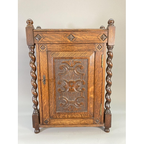 840 - A 1920s oak smoker's cabinet with barley twist supports, carved panelled door, two internal drawers ... 