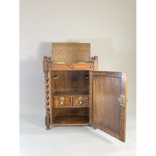 840 - A 1920s oak smoker's cabinet with barley twist supports, carved panelled door, two internal drawers ... 