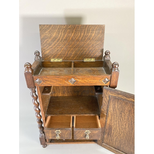 840 - A 1920s oak smoker's cabinet with barley twist supports, carved panelled door, two internal drawers ... 