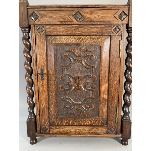 840 - A 1920s oak smoker's cabinet with barley twist supports, carved panelled door, two internal drawers ... 