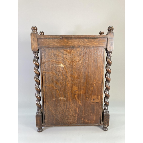 840 - A 1920s oak smoker's cabinet with barley twist supports, carved panelled door, two internal drawers ... 