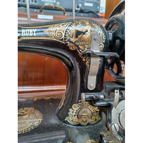 1535 - A cased antique The Royal Ruby hand crank sewing machine with attachments and a tin containing a col... 