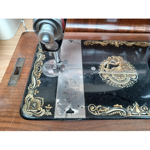 1535 - A cased antique The Royal Ruby hand crank sewing machine with attachments and a tin containing a col... 