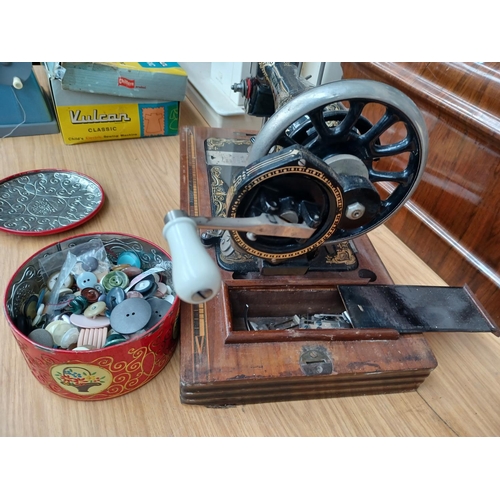 1535 - A cased antique The Royal Ruby hand crank sewing machine with attachments and a tin containing a col... 