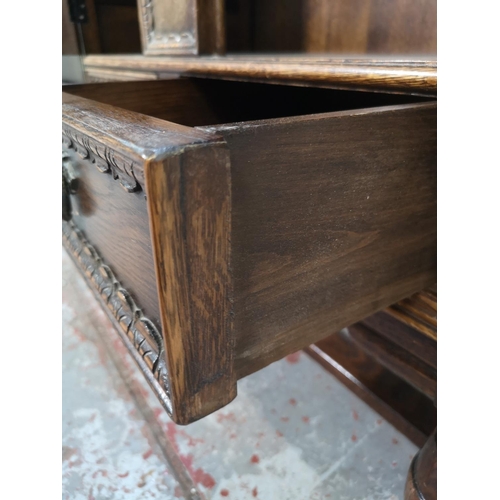 325 - A 17th century style carved oak side cabinet with two cupboard doors and two lower drawers - approx.... 