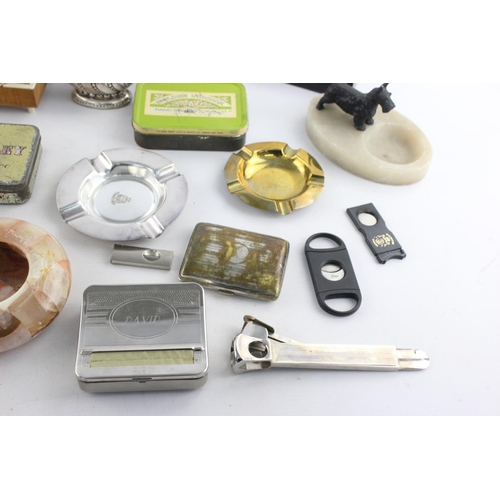 107 - A collection of assorted smoking accessories to include dispenser, tins, ashtrays etc.