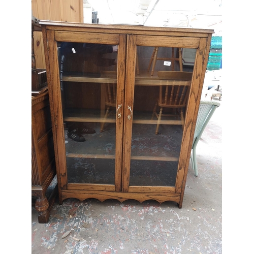 323 - A mid 20th century oak two door glazed bookcase with three internal shelves - approx. 122.5cm high x... 