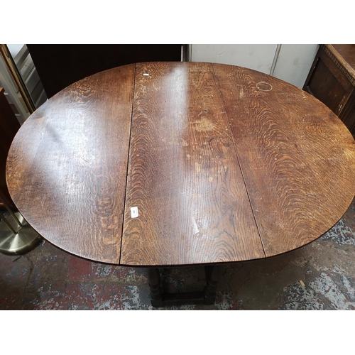 326 - An oak drop leaf gate leg oval dining table - approx. 76cm high x 109cm wide x 132cm extended