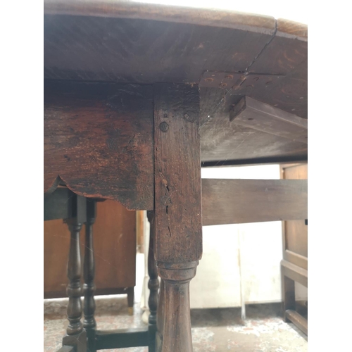 326 - An oak drop leaf gate leg oval dining table - approx. 76cm high x 109cm wide x 132cm extended