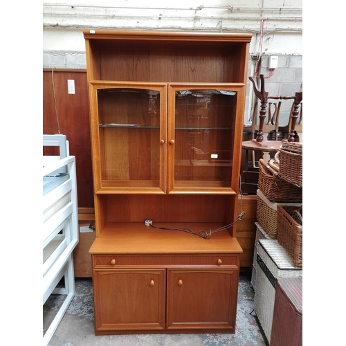 338 - A Morris of Glasgow teak display cabinet with two upper bevelled glass doors, one long drawer and tw... 