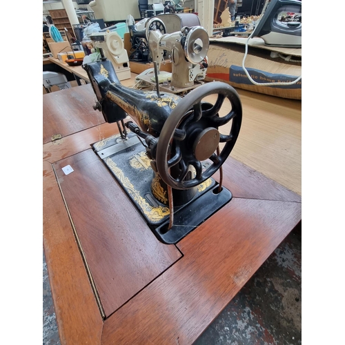 790 - An early 20th century mahogany sewing machine cabinet containing Singer treadle sewing machine (seri... 