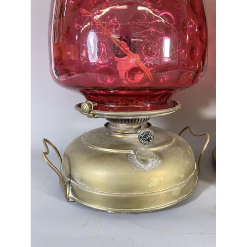 132 - Two antique brass electric converted oil lamps with cranberry glass shades - largest approx. 28cm hi... 